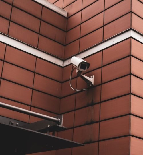 Security camera monitoring a red brick building exterior, symbolizing modern surveillance in Germany.